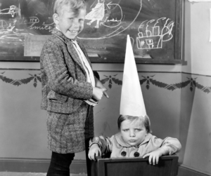 Shame guilt. Kid with dunce cap in trashcan and other kid smiling